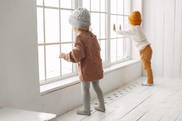 kids wearing winter caps enjoying near window