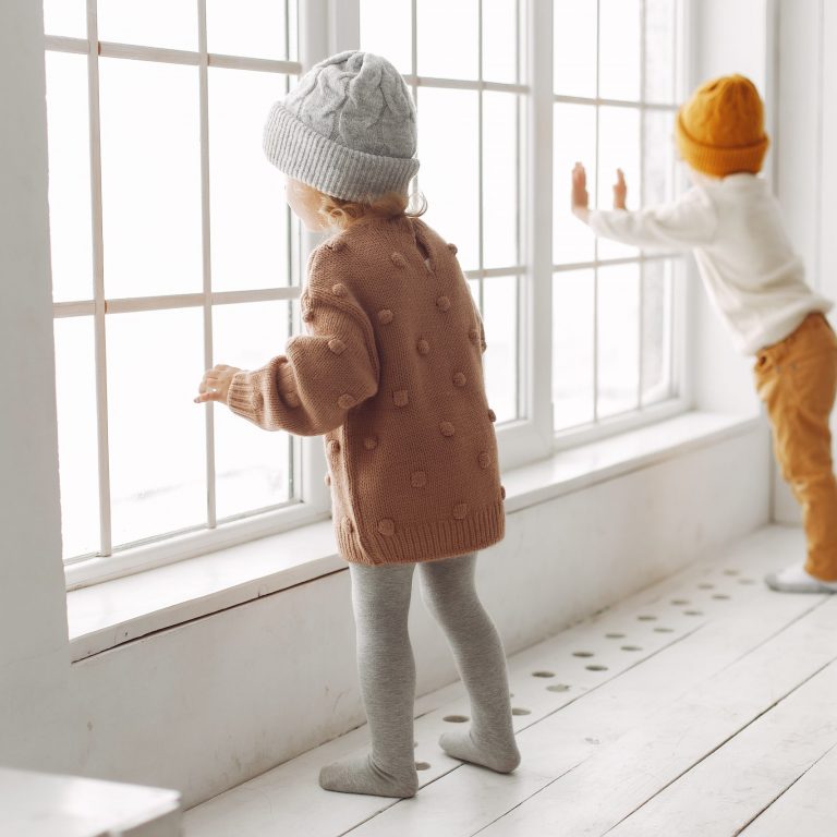 kids wearing winter caps enjoying near window